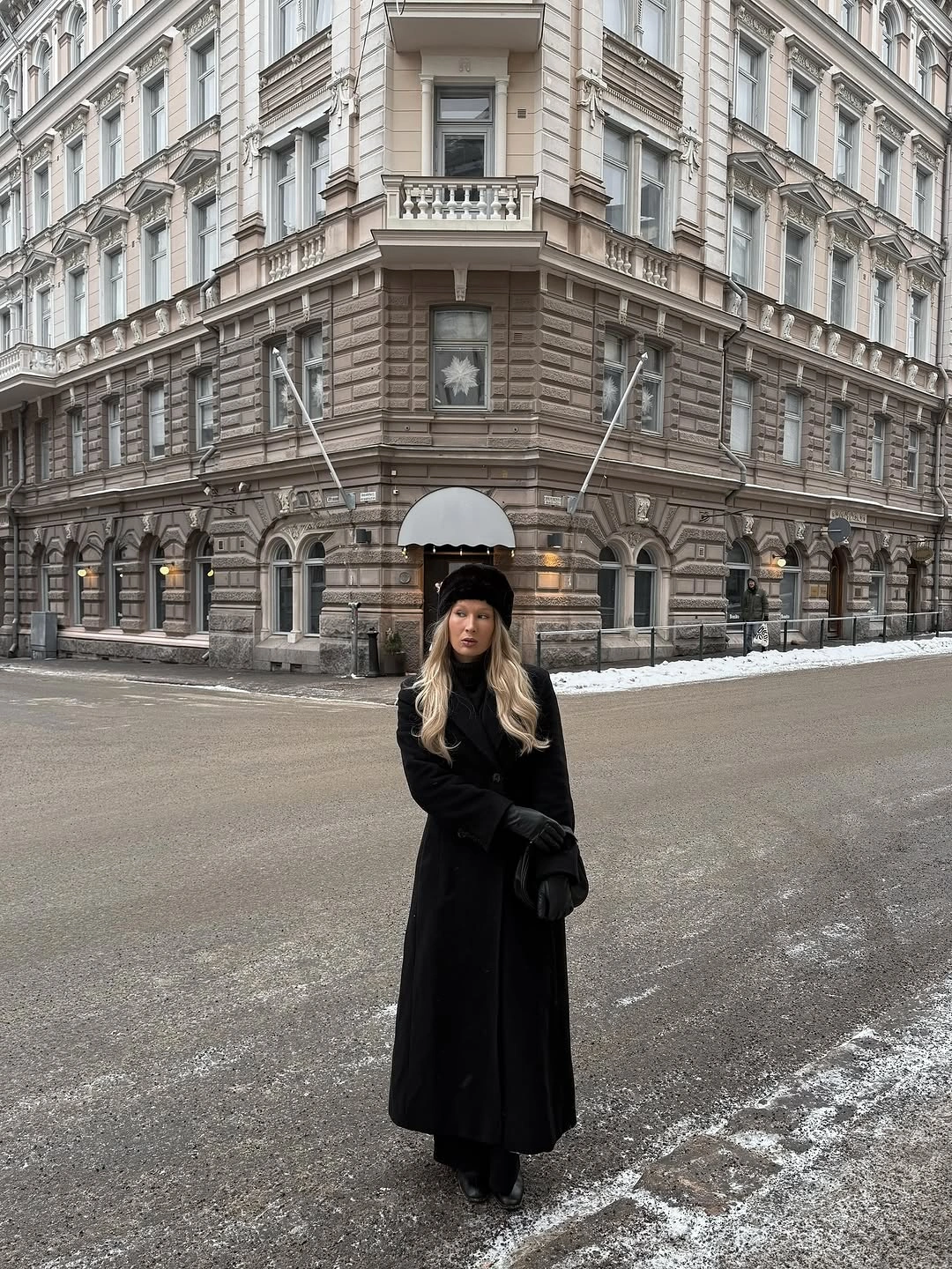 Long black coat with knit hat gloves and compact black crossbody bag