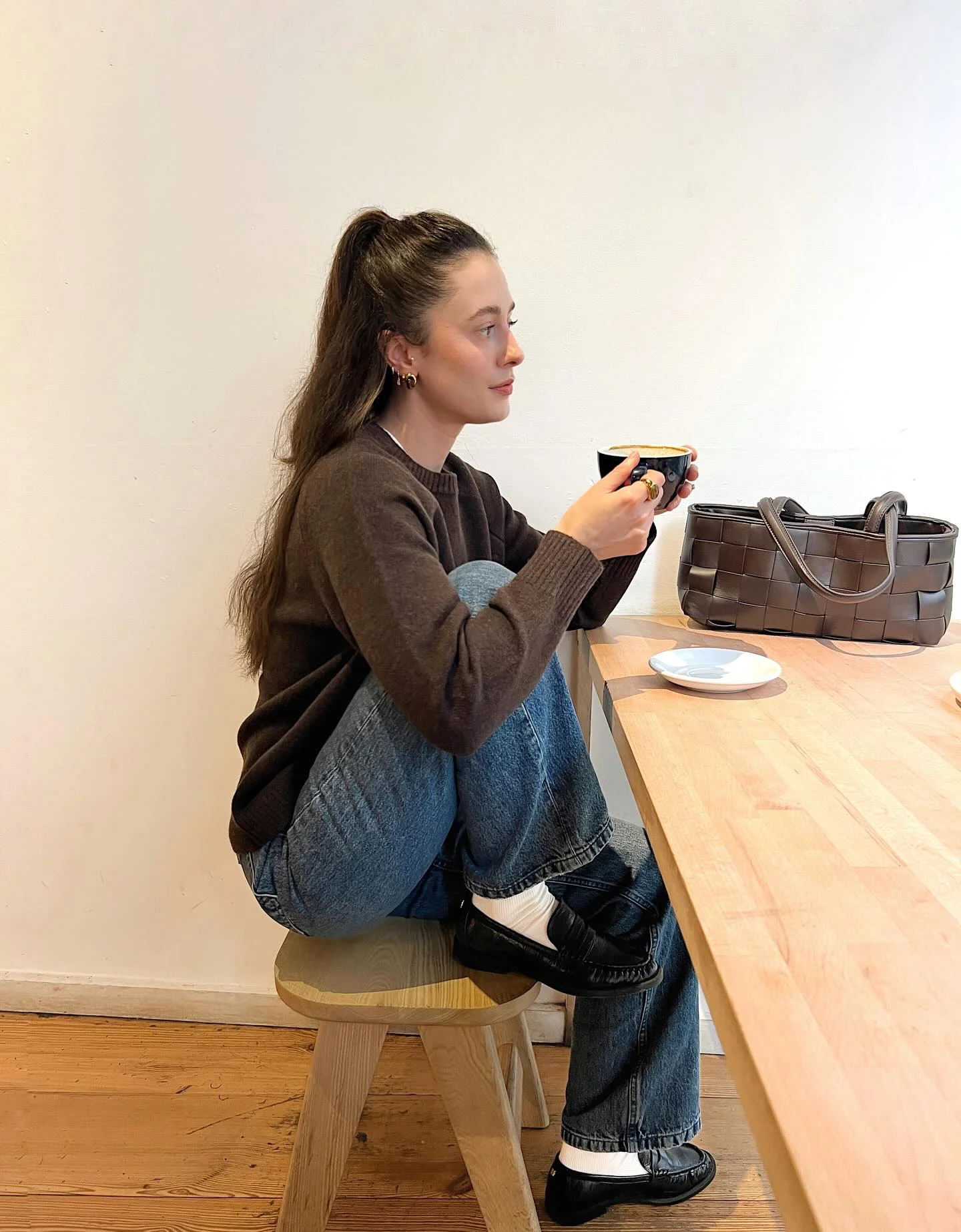 Brown ribbed sweater blue jeans black knee-high boots and brown handbag