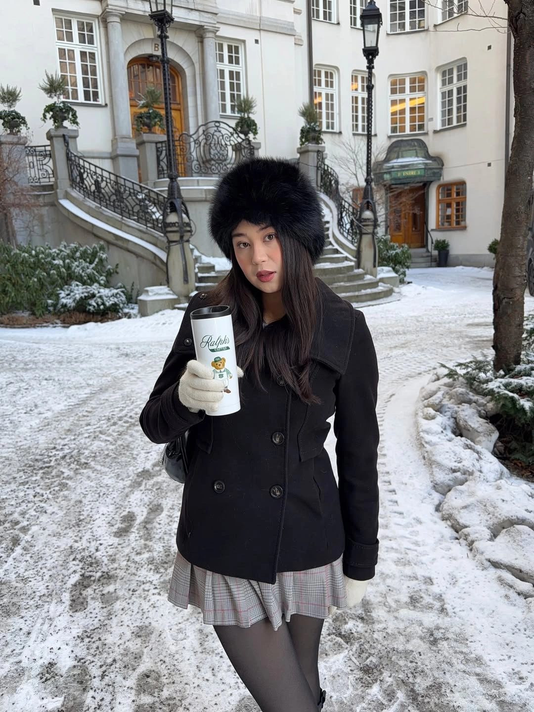 Black tailored coat gray pleated mini skirt tall boots and furry hat