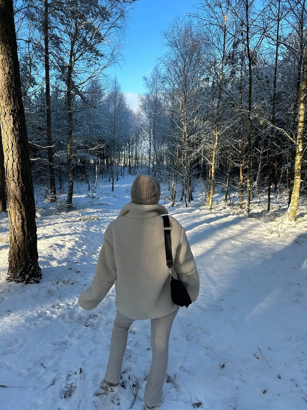 Oversized beige hoodie with gray leggings black shoulder bag and beanie in snow