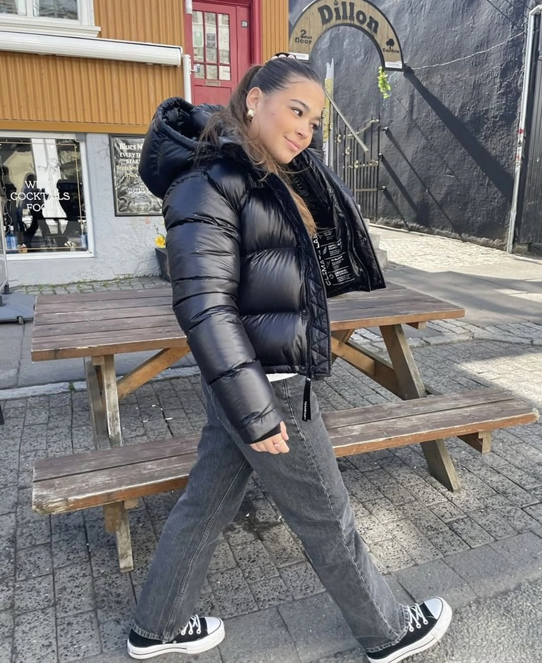 Black puffer-style jacket with gray jeans and high-top sneakers