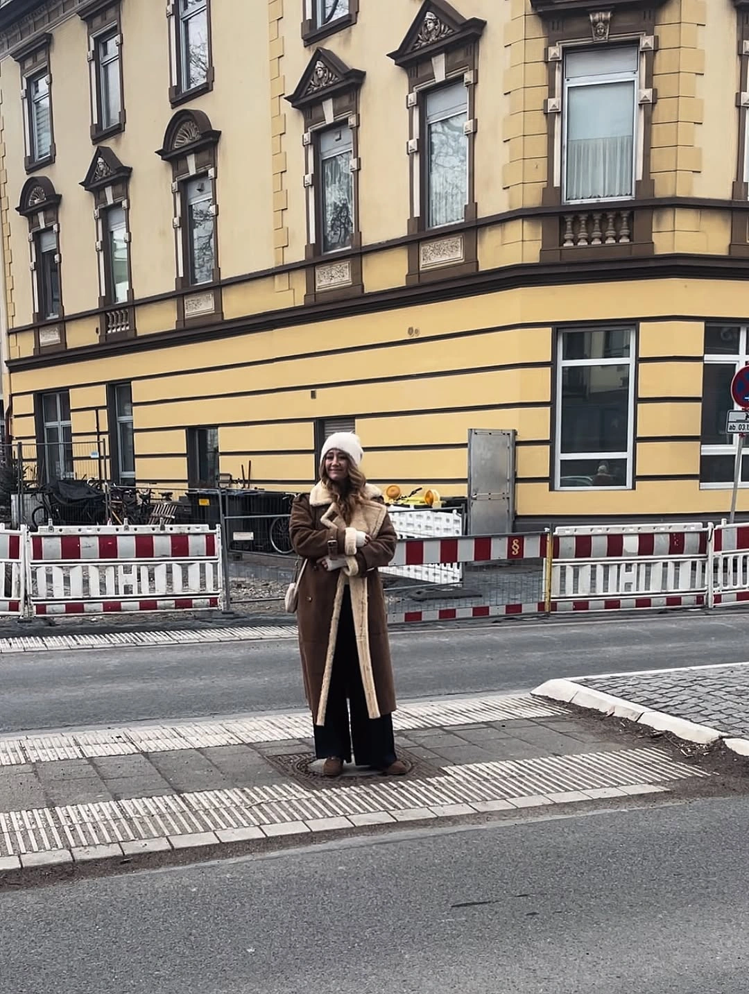 Long brown shearling-style coat with cream scarf and hat