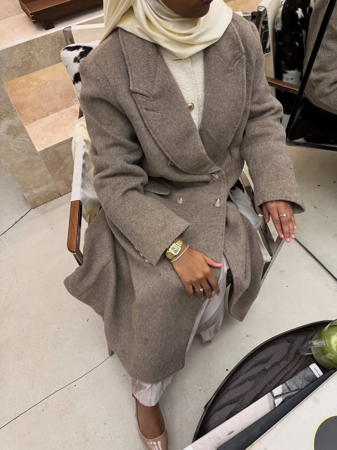 Taupe-gray double-breasted coat with light scarf and pale trousers