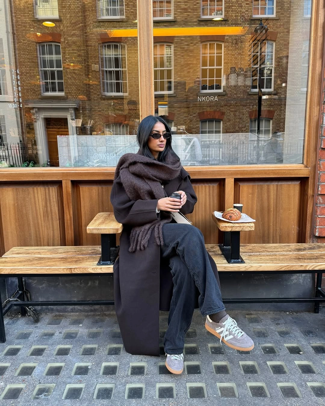 Dark long coat with brown scarf jeans and gray sneakers