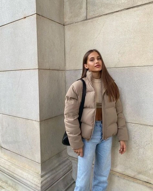 Beige cropped puffer with taupe sweater, blue jeans and black bag