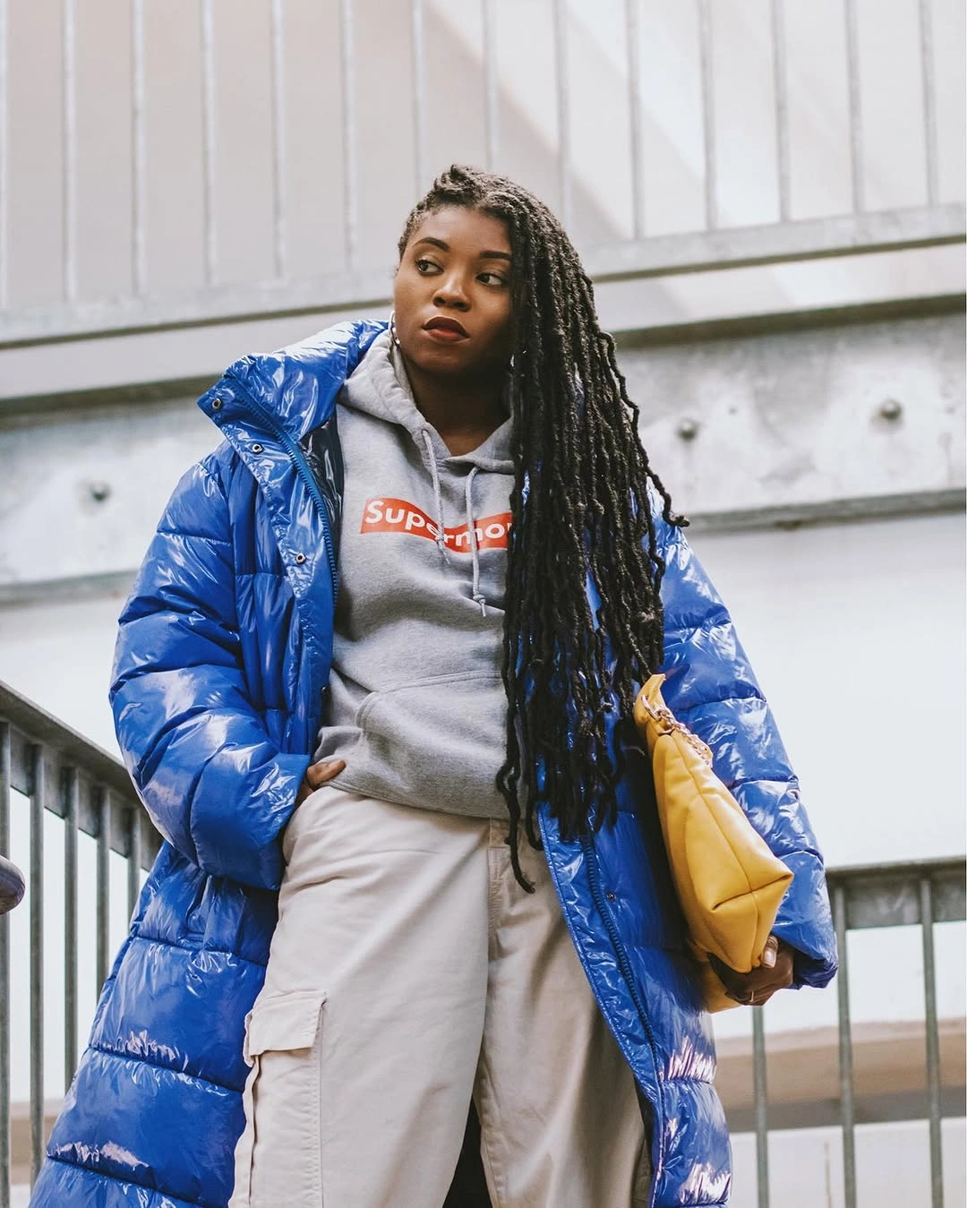 Blue long puffer with gray hoodie, light trousers and yellow bag