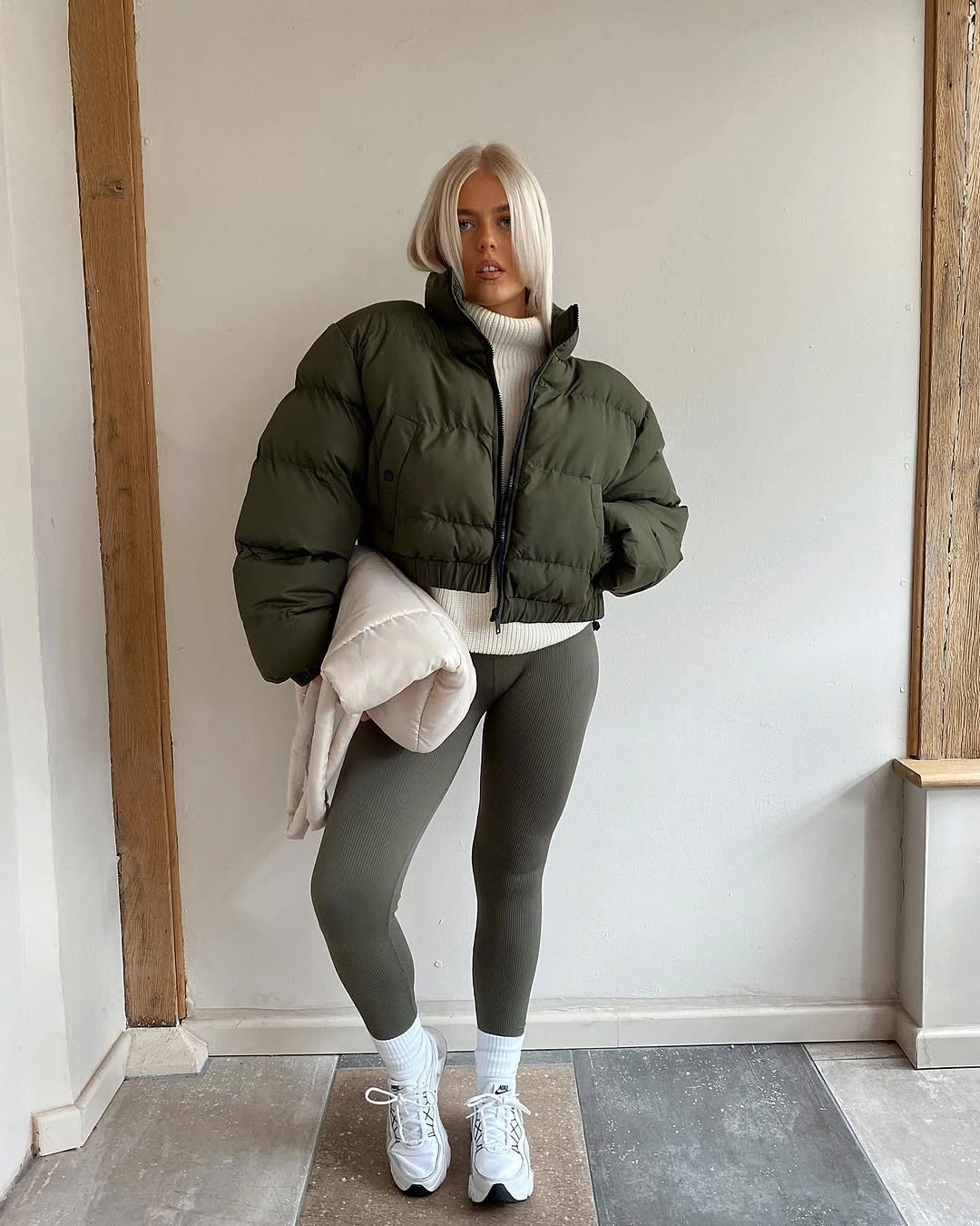 Olive cropped puffer with cream turtleneck, gray leggings and sneakers