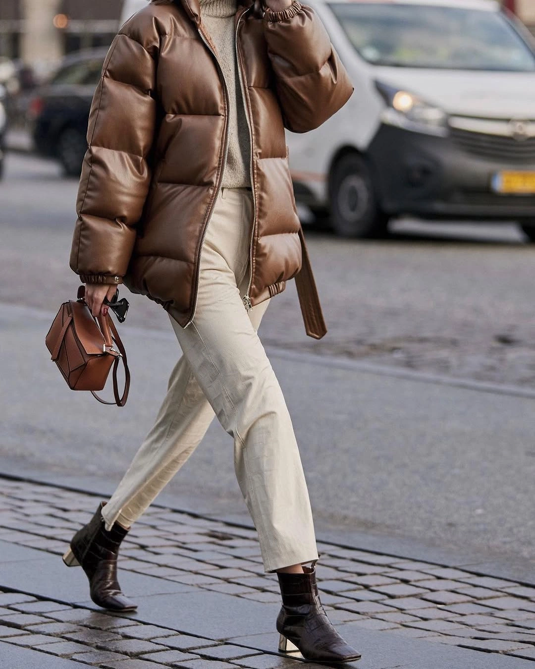 Shiny brown puffer with cream outfit, black boots and handbag