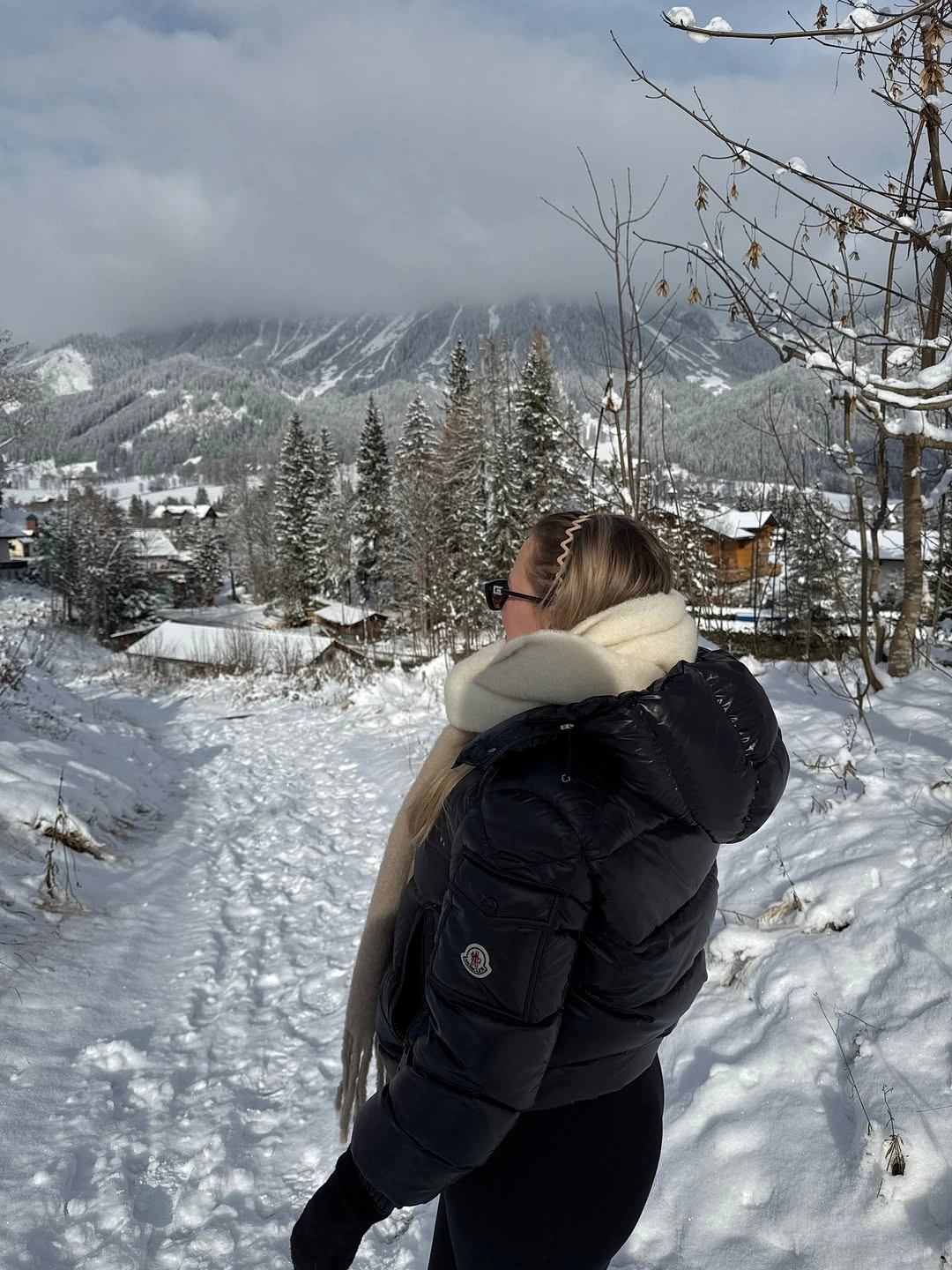 Black puffer jacket with cream scarf in snowy mountain setting