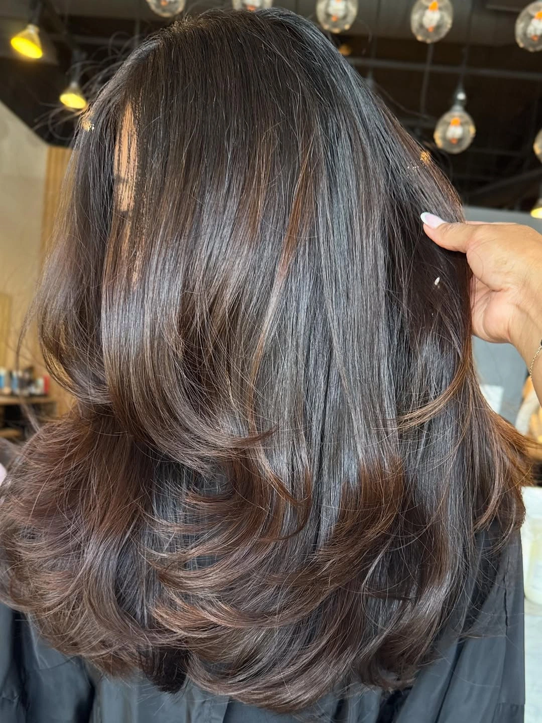 Rear view of long dark layered haircut with curved ends