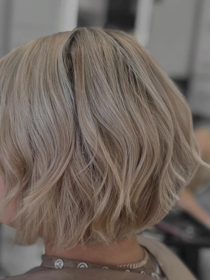 Rear view of short ash blonde wavy bob haircut