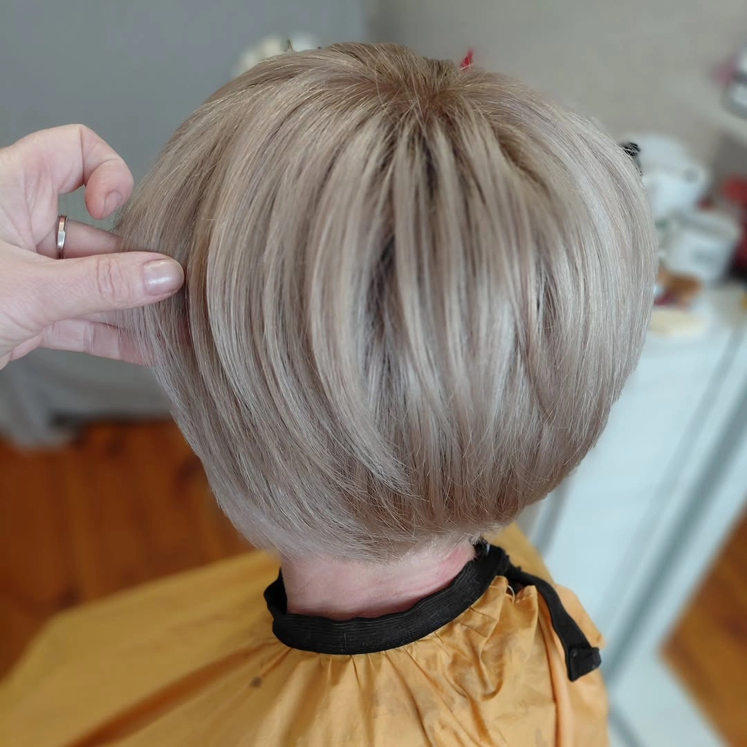 Back view of rounded pale blonde pixie haircut