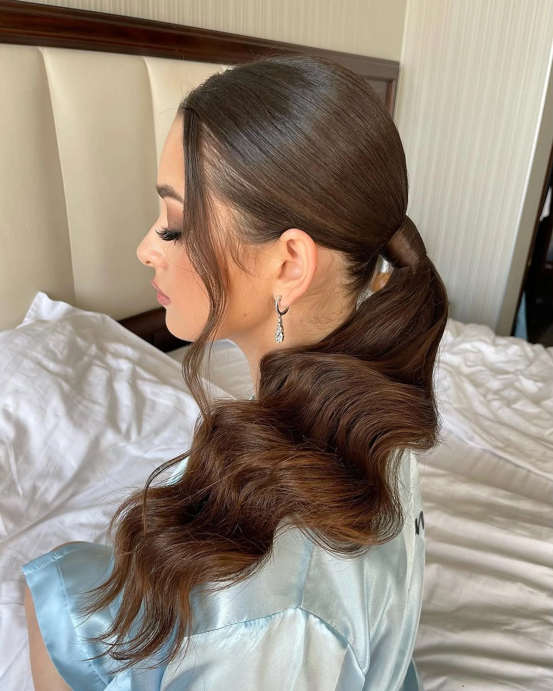 Low brunette ponytail with broad curled tail