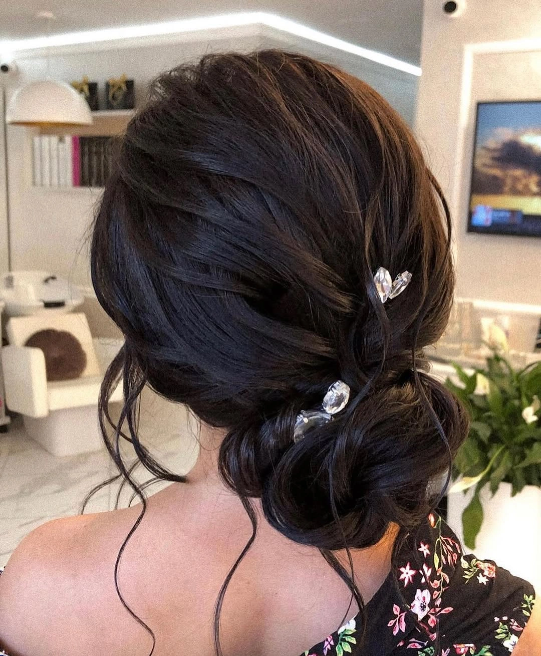 Dark low updo with loose tendrils and pins
