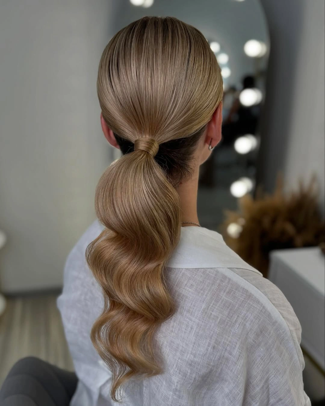 Blonde low ponytail with smooth crown and wavy tail