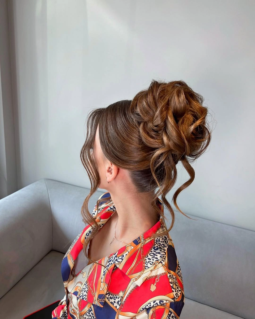 Warm brown curled updo with loose spiral tendrils