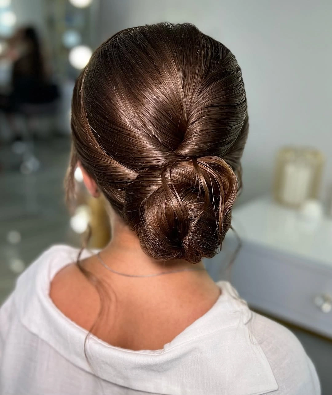 Glossy brunette low bun with wrapped nape detail