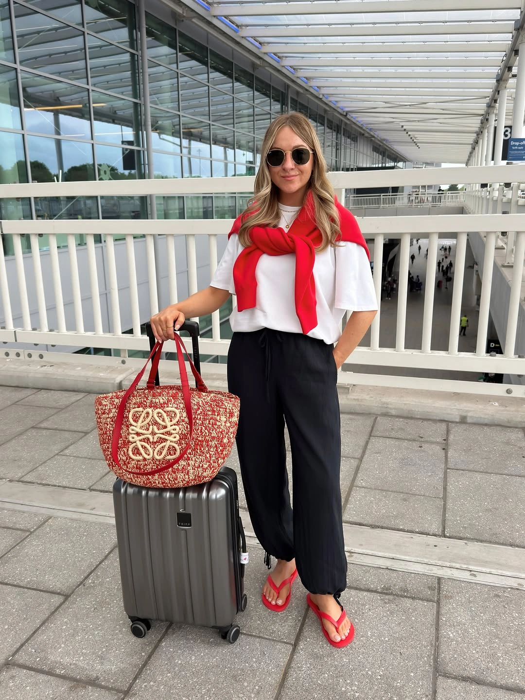White tee with black pants, red accents and suitcase