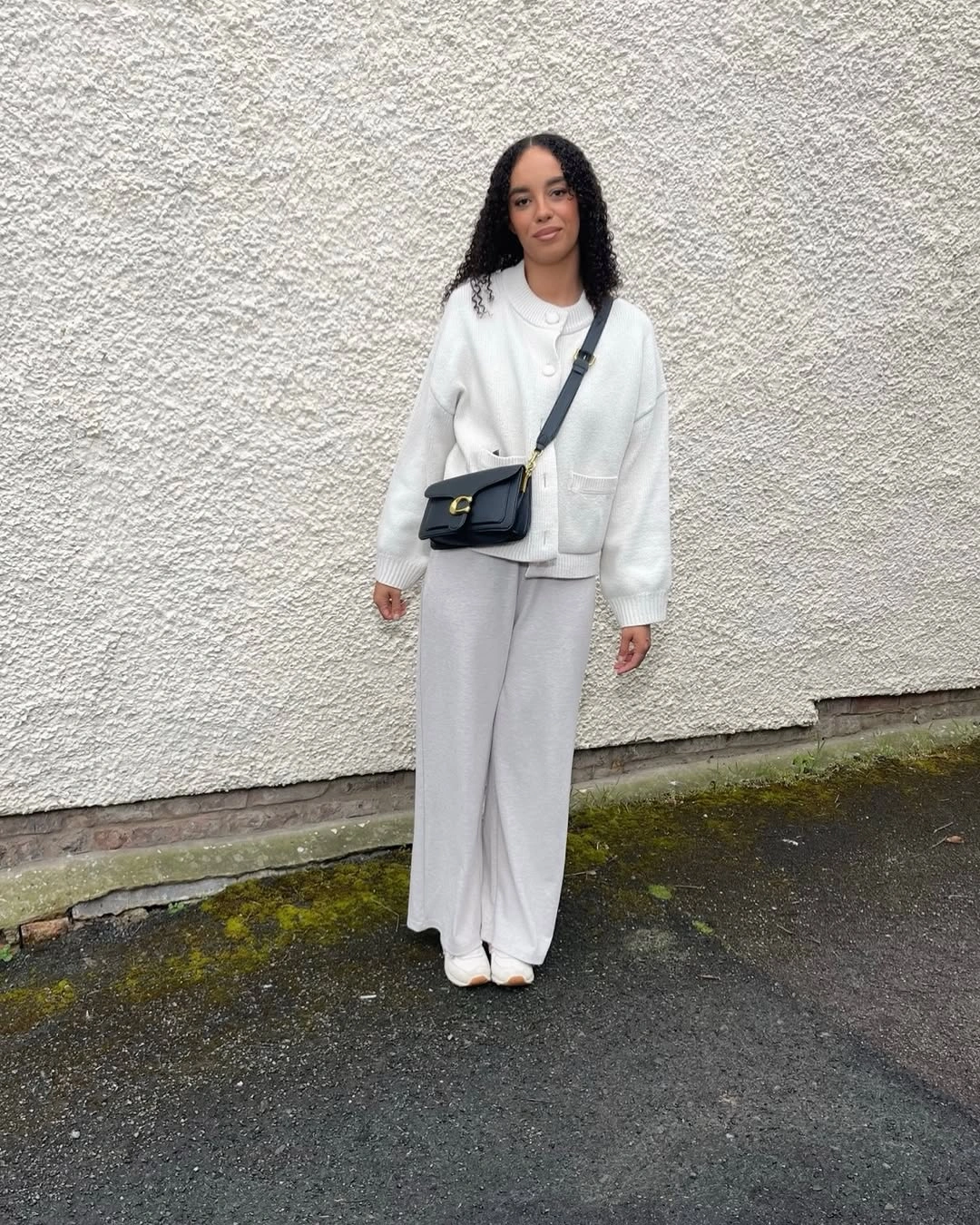 Cream cardigan top with wide trousers and black crossbody