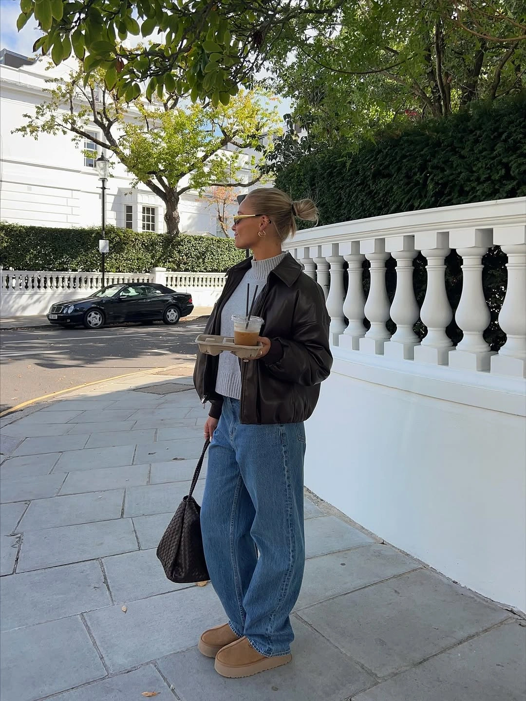 Dark jacket with wide jeans, tan platforms and drink tray