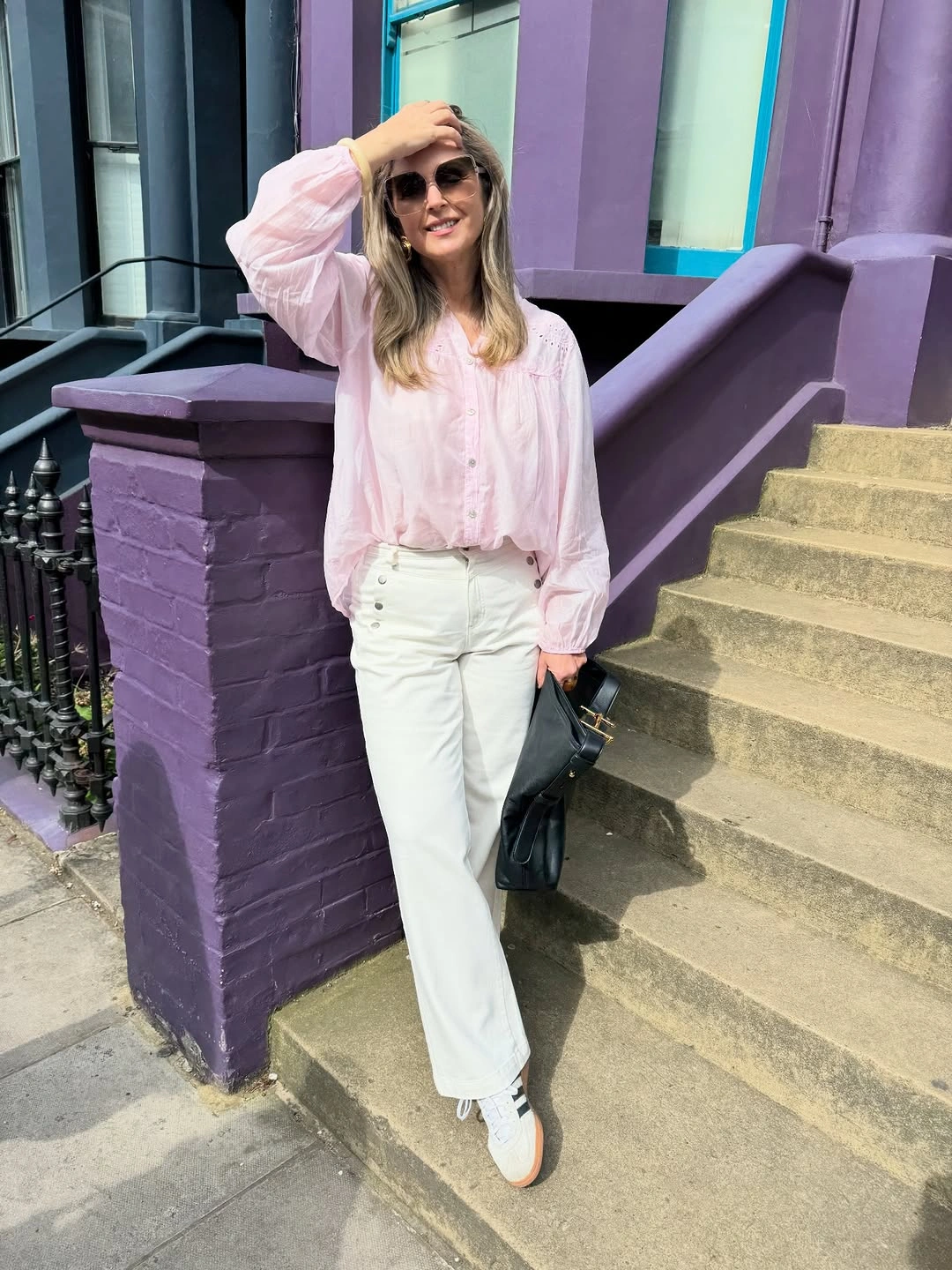 Pale pink blouse with white jeans, sneakers and black handbag