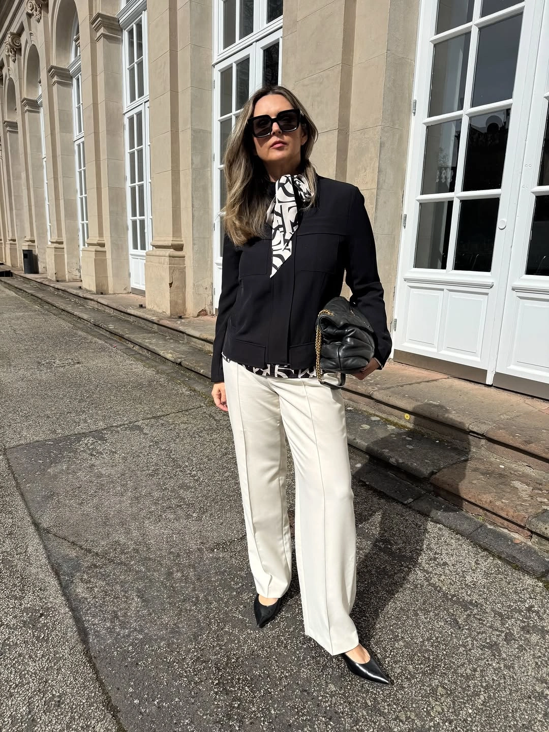 Black jacket with white wide-leg trousers and pointed shoes