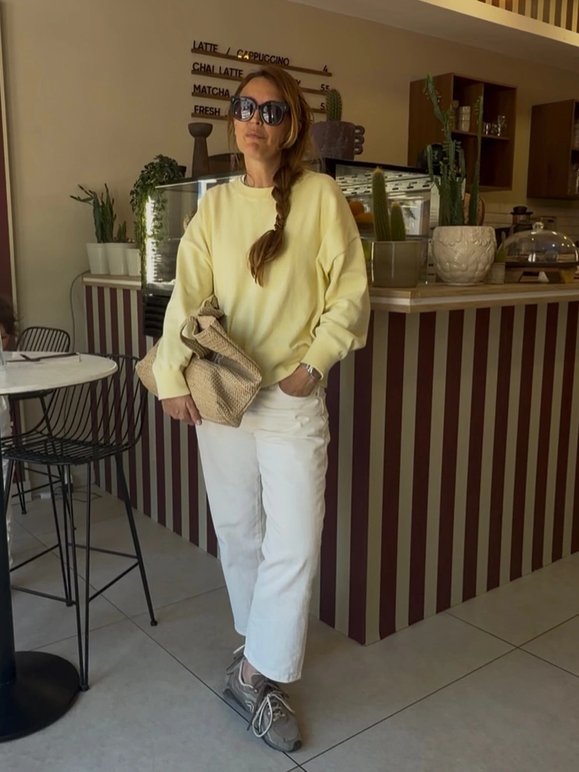Pale yellow sweatshirt with white cropped pants and gray sneakers