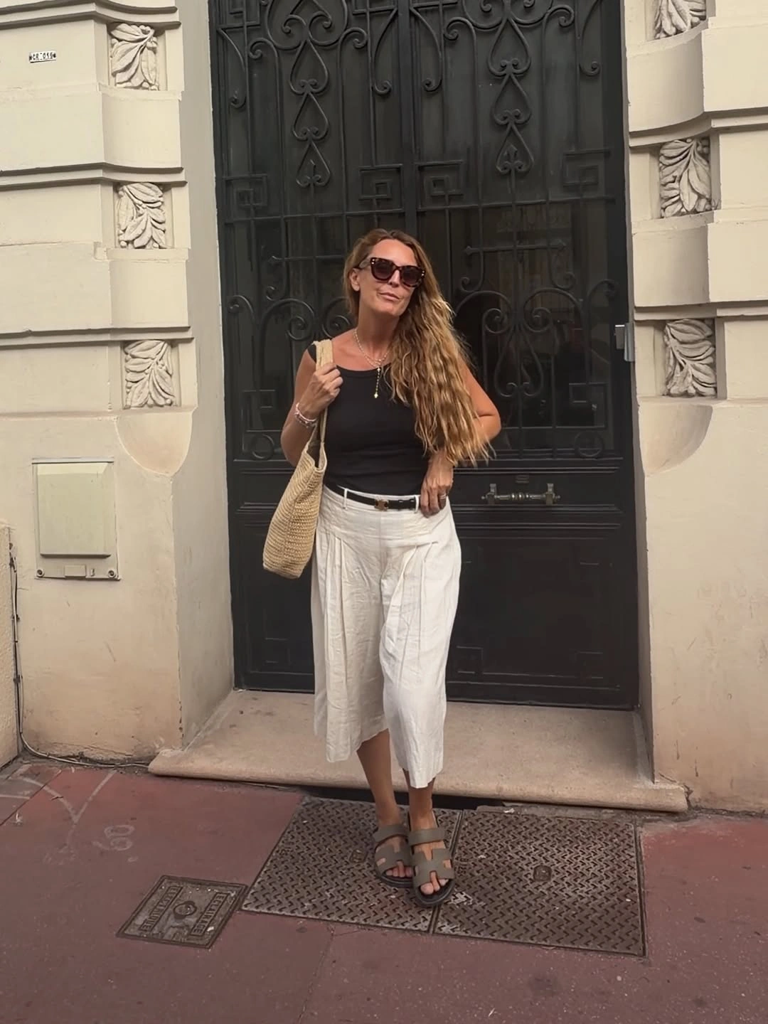 Black sleeveless top with cropped white pants and woven tote