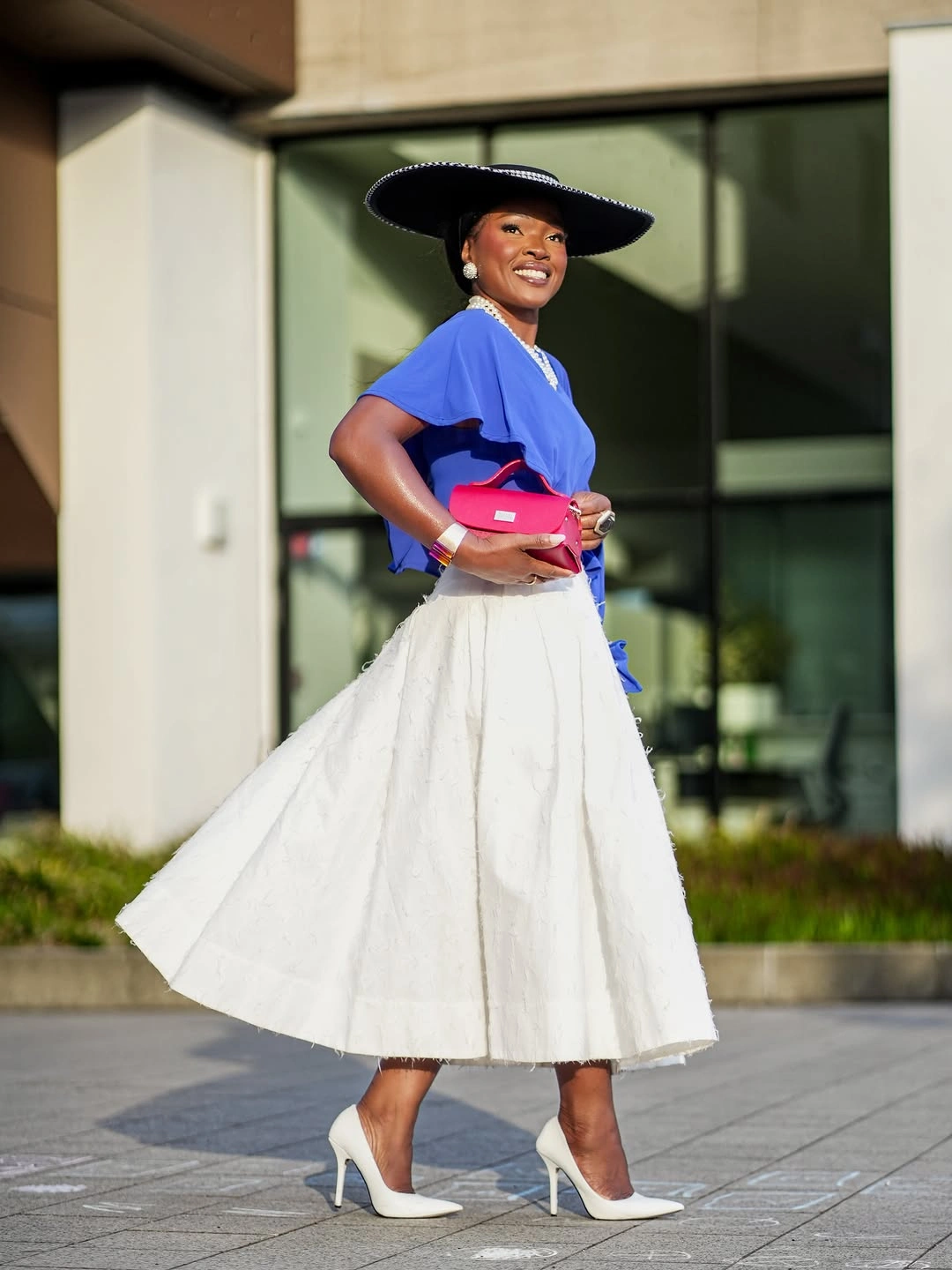 Bright blue top with full white skirt and black hat