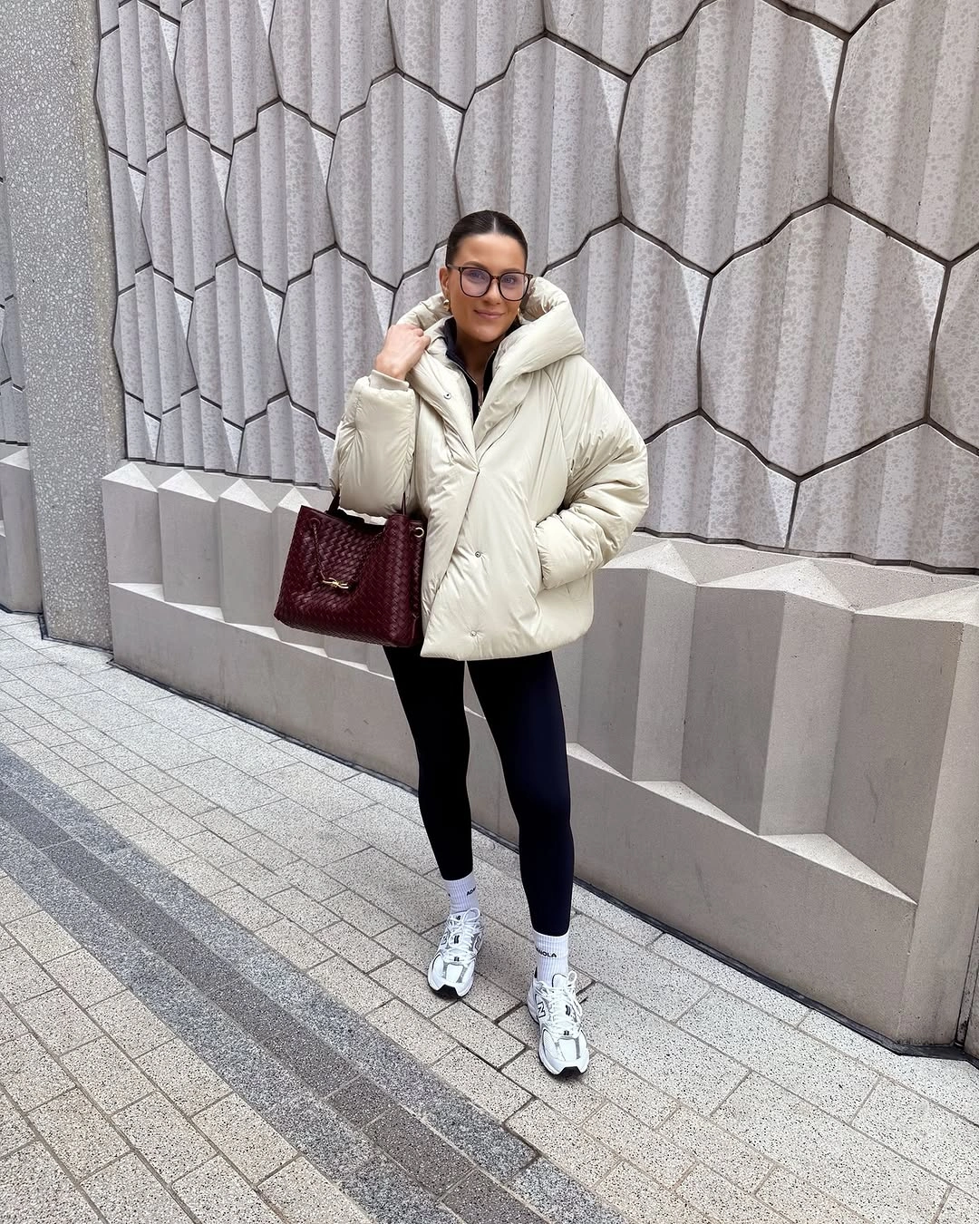 Cream puffer with black leggings white sneakers and burgundy handbag