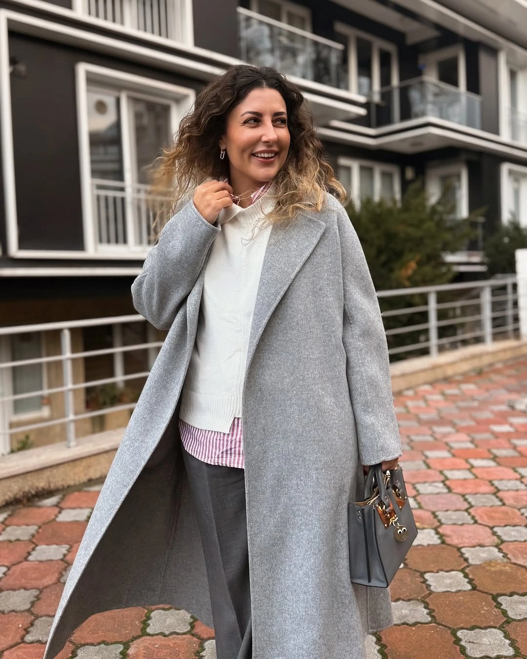 Gray coat white top gray trousers and handbag