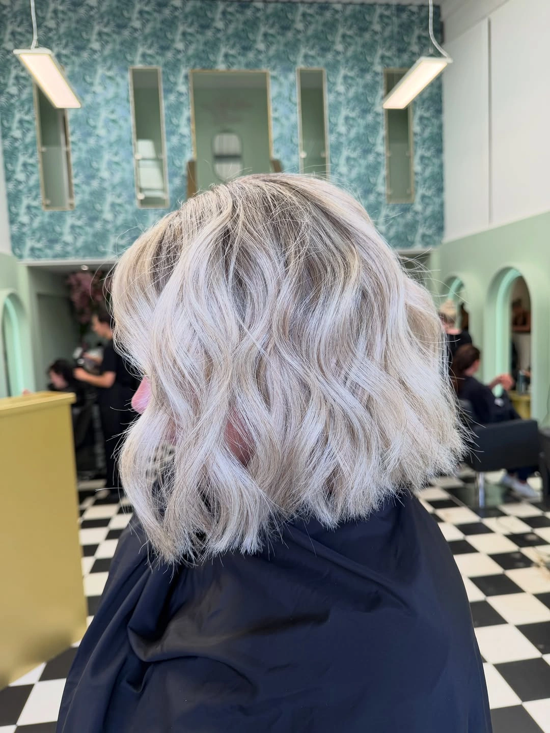Short silver ash wavy bob with darker roots