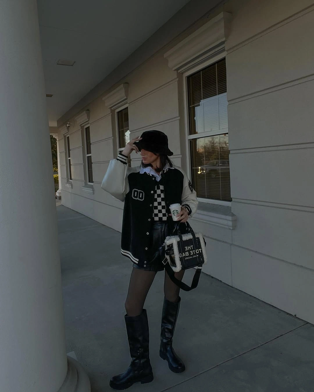 Black and white varsity jacket with checkerboard knit and tall boots