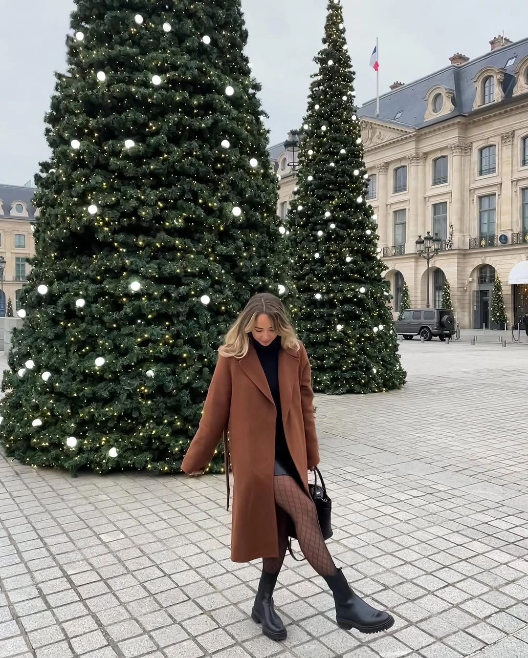 Camel long coat with black skirt, patterned tights, and chunky boots