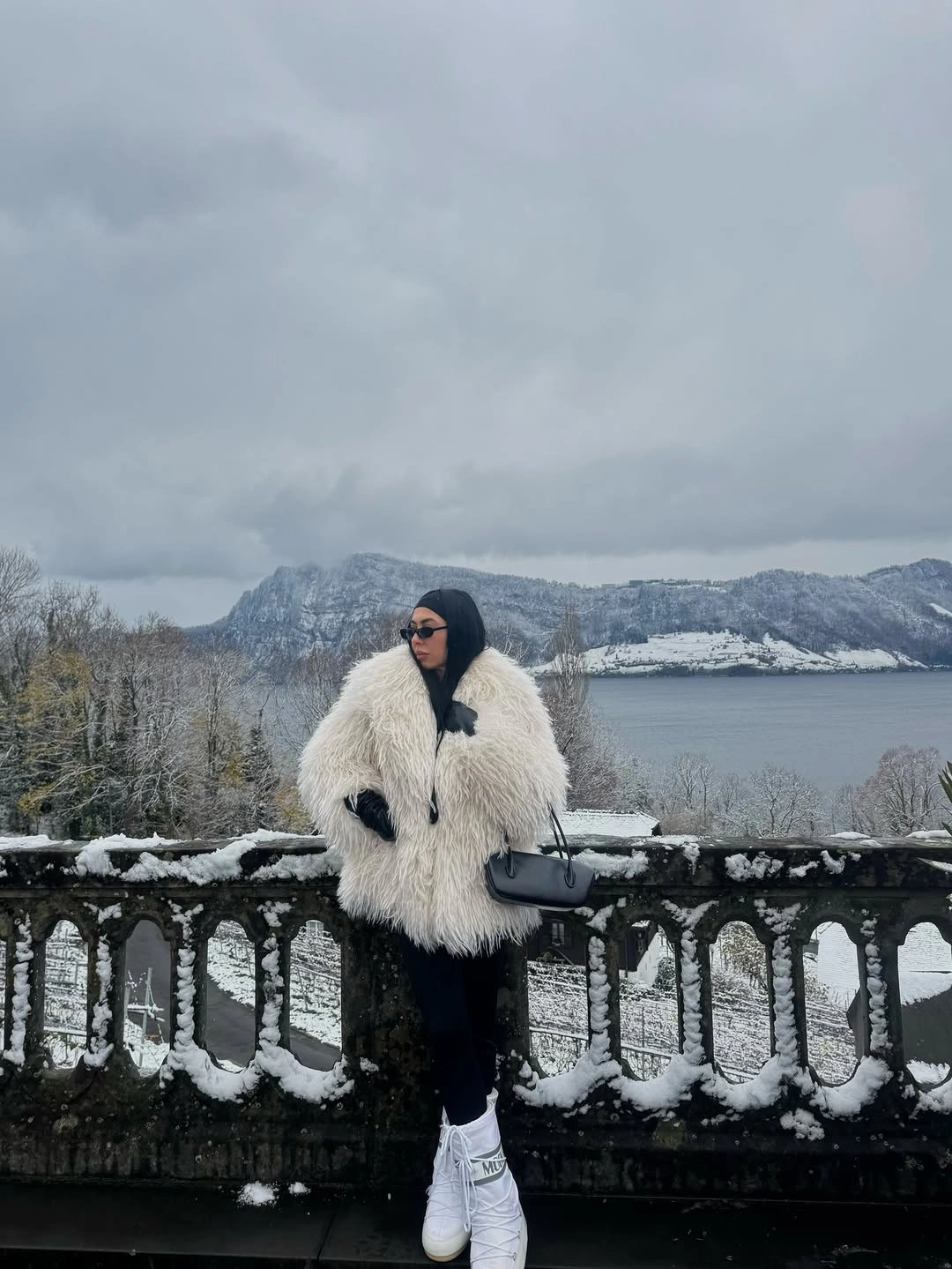 White shaggy-looking coat over black base with white sneakers near snow
