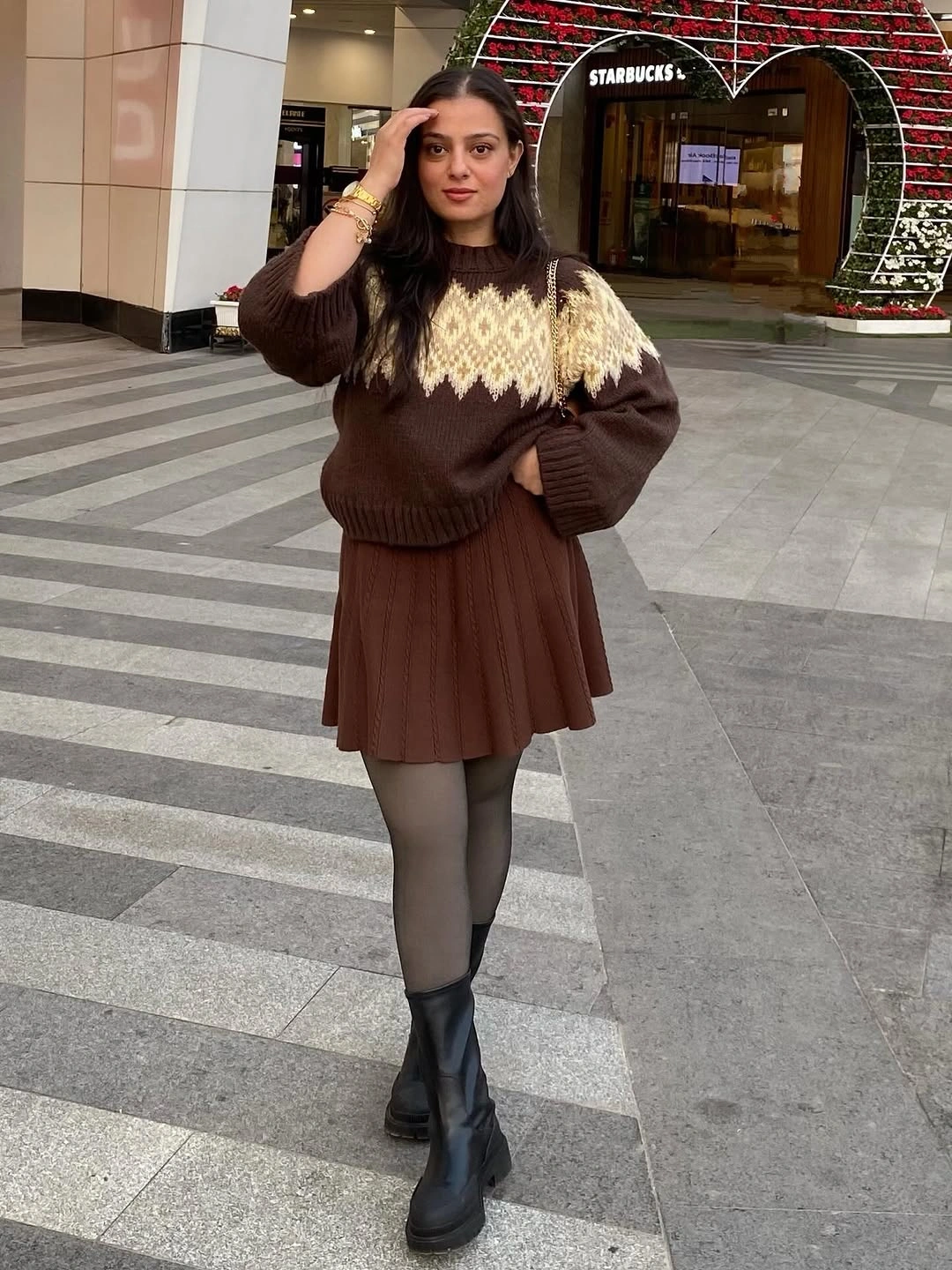 Brown sweater with cream yoke pattern, pleated skirt, tights, boots