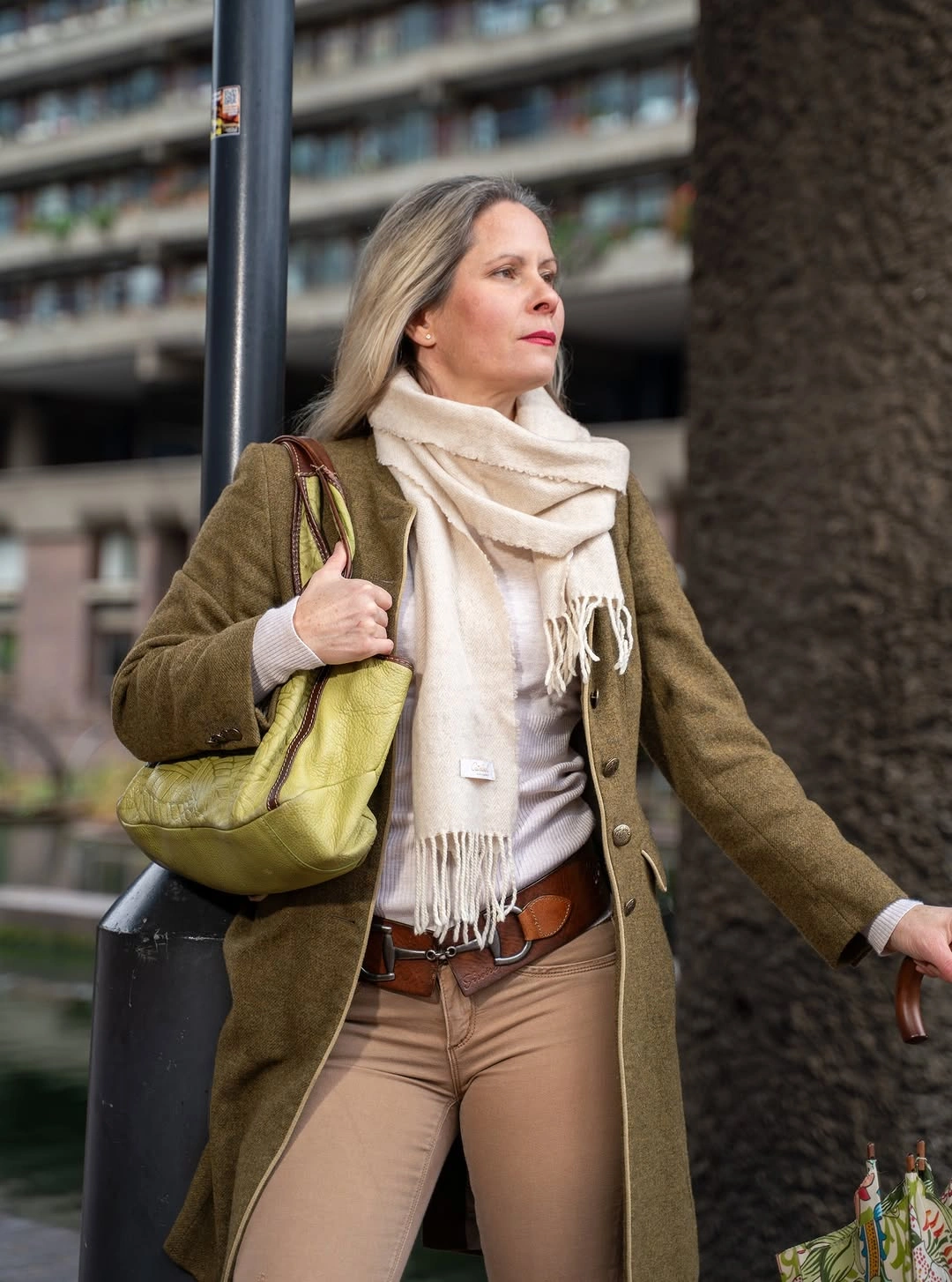 Olive-brown coat, cream scarf, tan trousers, lime handbag