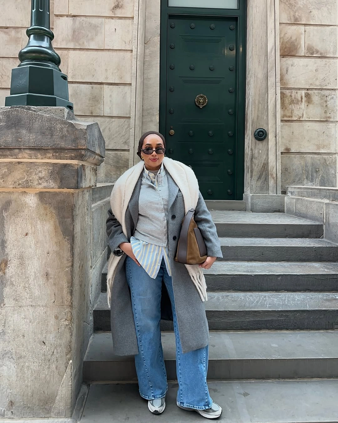 Long gray coat, cream scarf, pale jeans, white sneakers