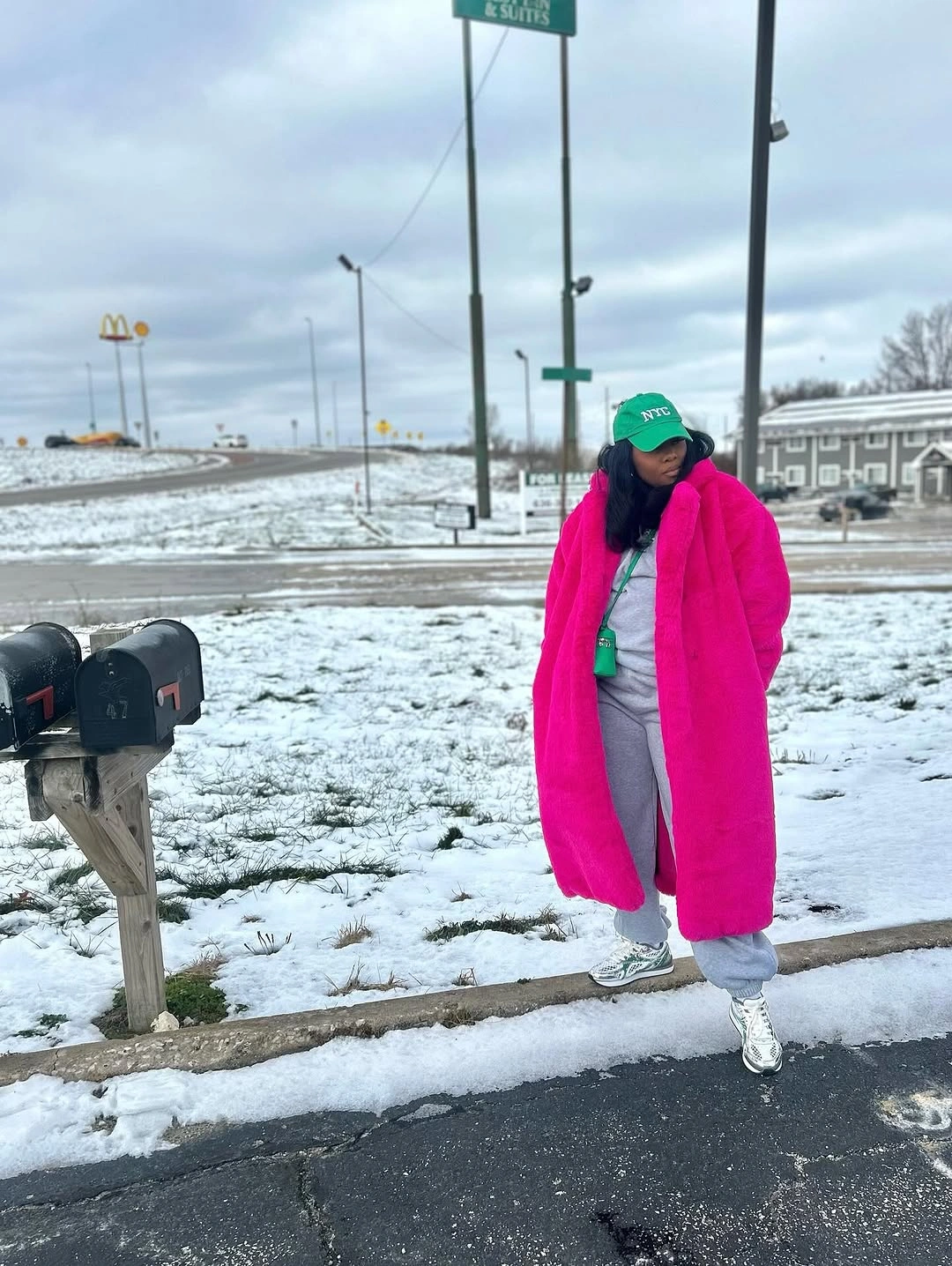 Bright fuchsia long puffer coat, gray trousers, white sneakers, green cap