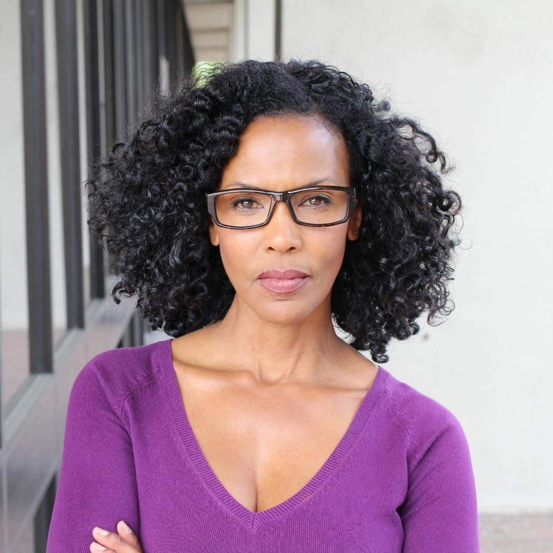 Shoulder-length black curls with side part and compact rounded shape