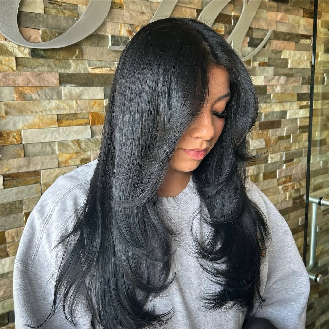 Very long near-black hair with sweeping layers and curved ends