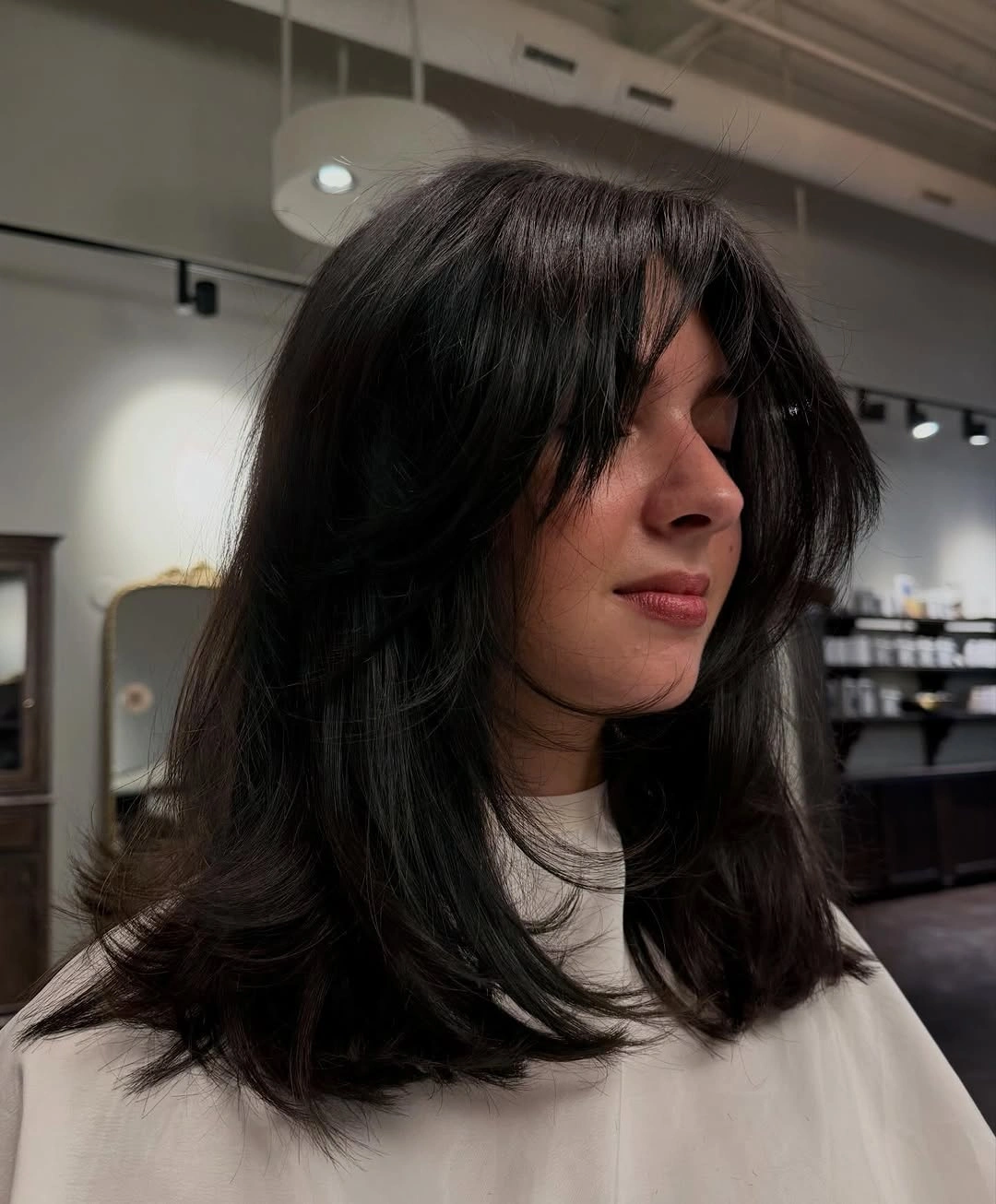 Dark shoulder-length hair with face-framing layers and flipped ends