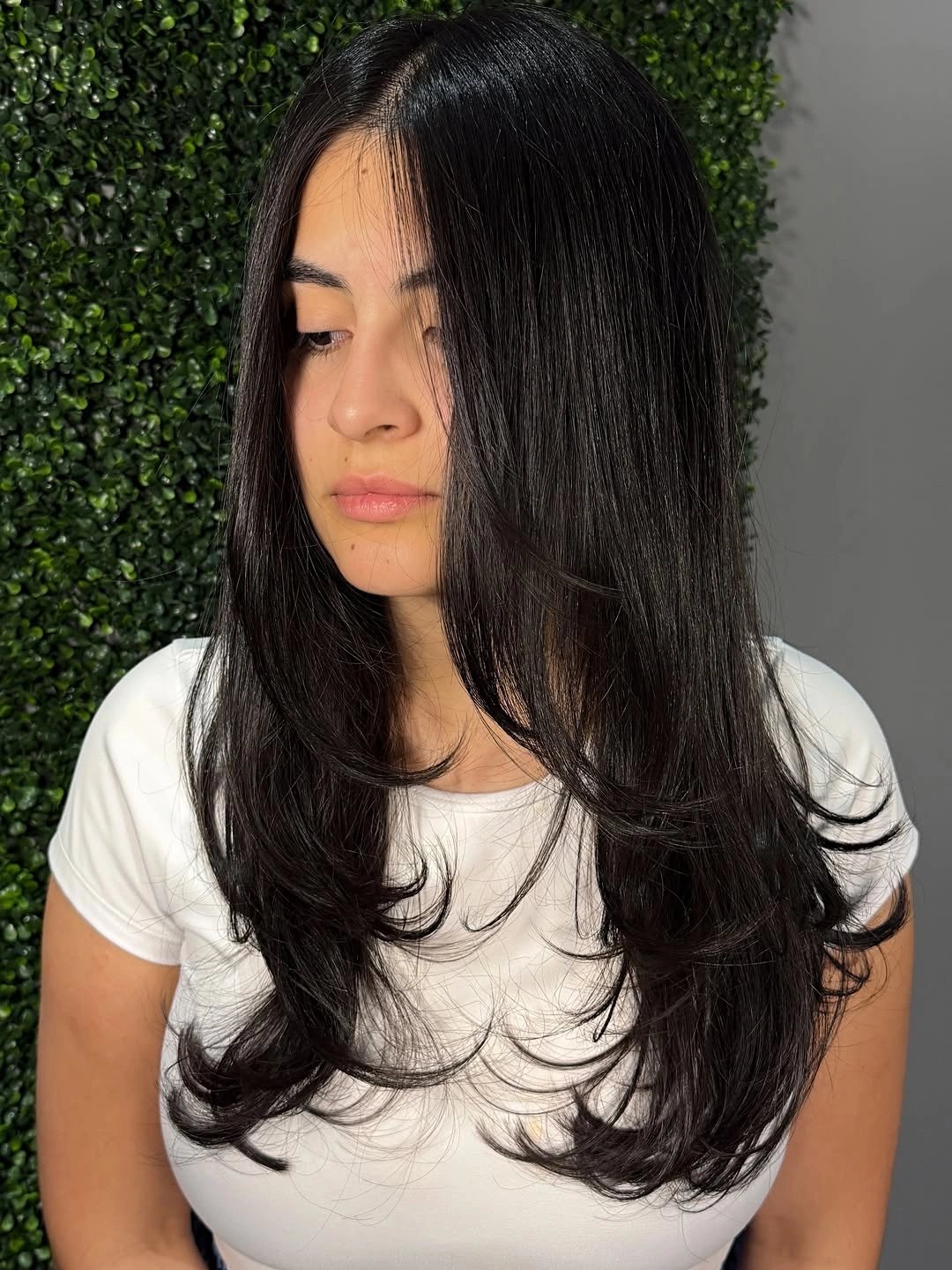 Long black center parted hair with curled layered ends