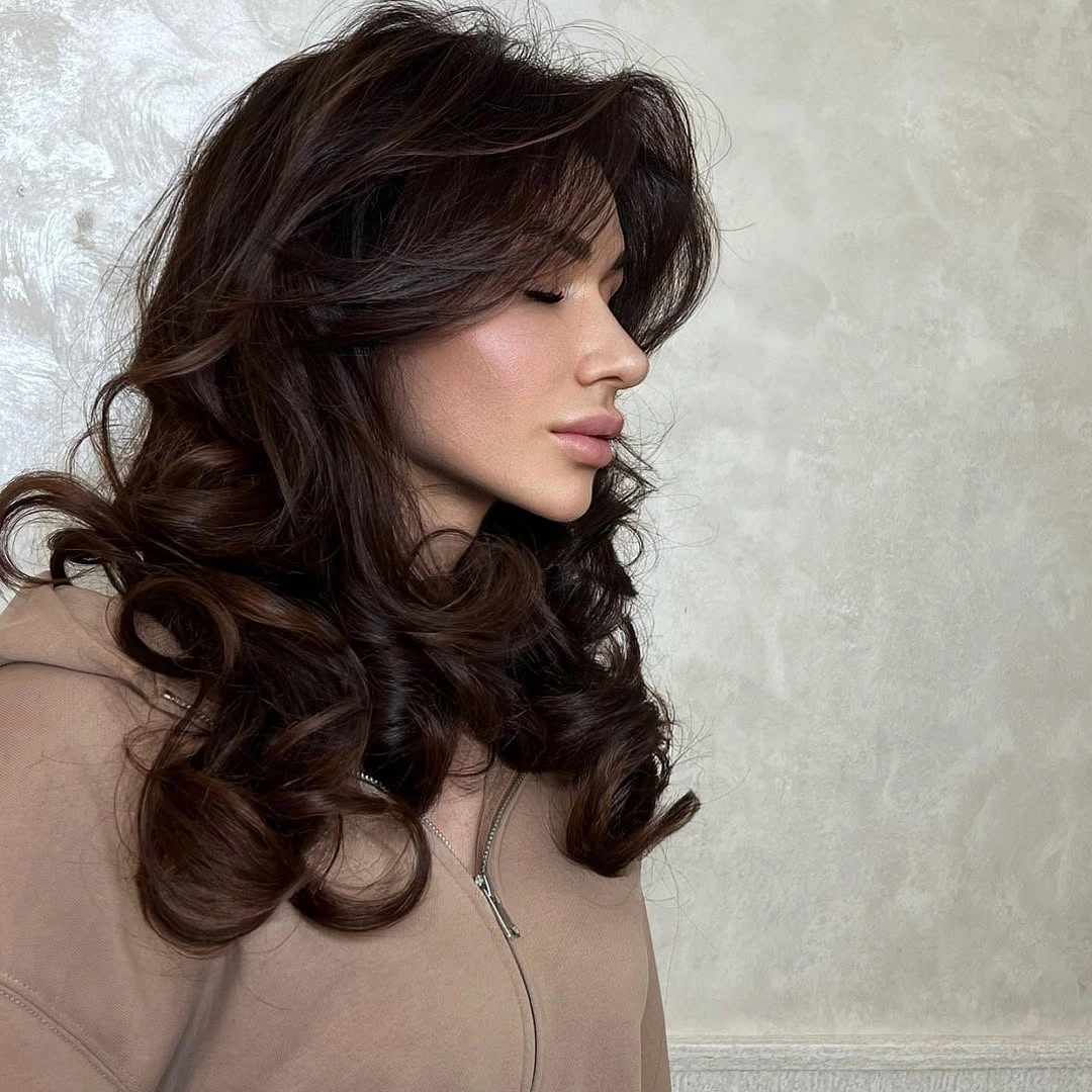 Long dark layered hair with loose curls and side volume