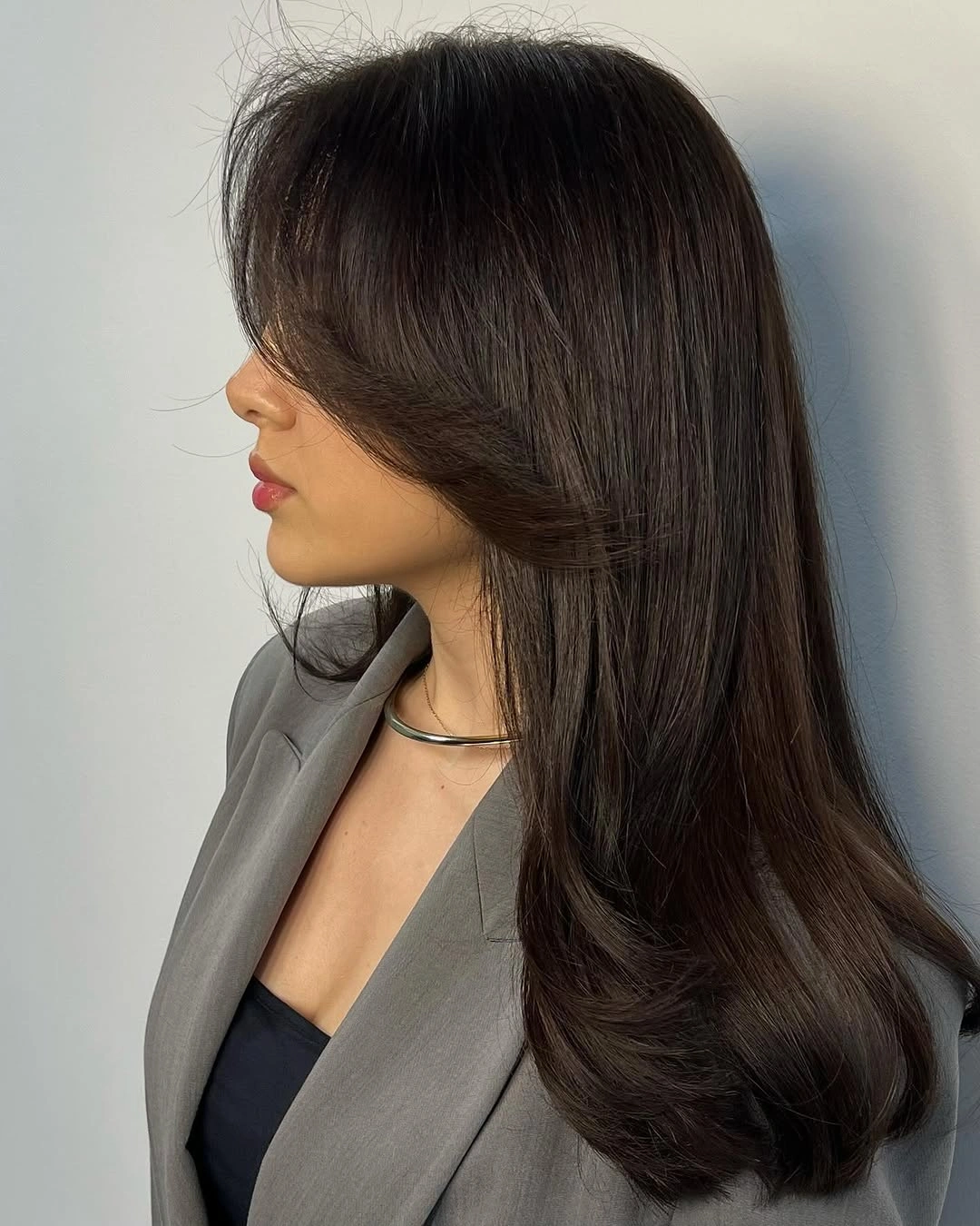 Long dark side view haircut with sleek layers and inward ends