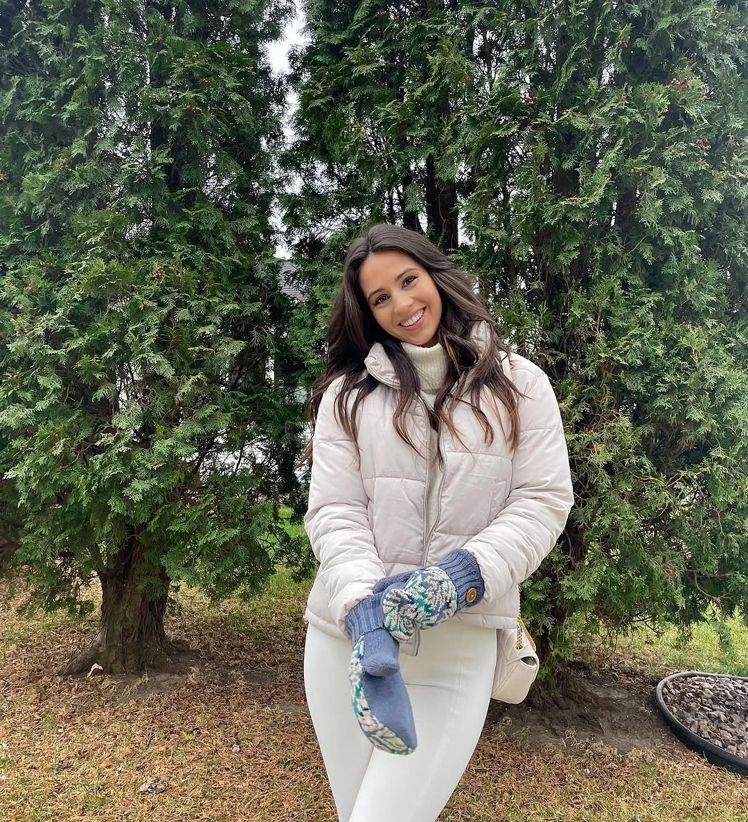 Pale blush puffer with white trousers, patterned mittens, and light bag