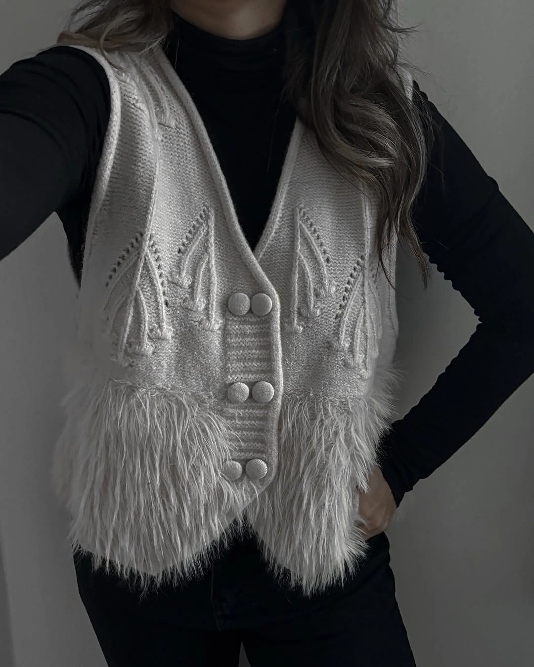 Cropped gray textured-looking vest over black top and black bottoms
