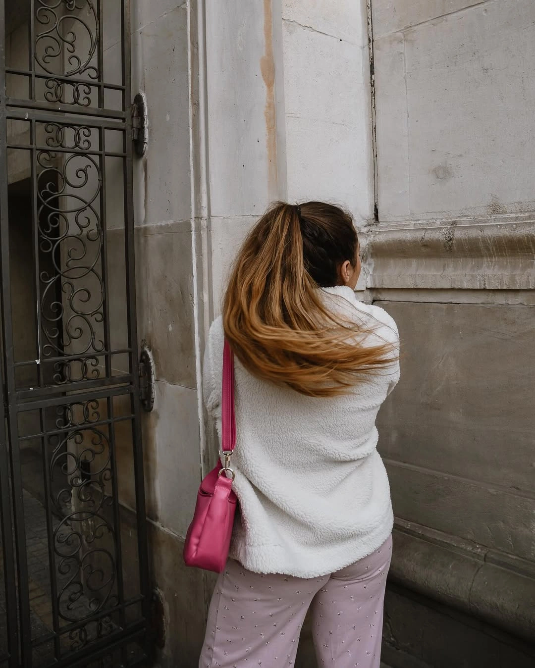 White textured-looking jacket, pale trousers, and vivid pink shoulder bag