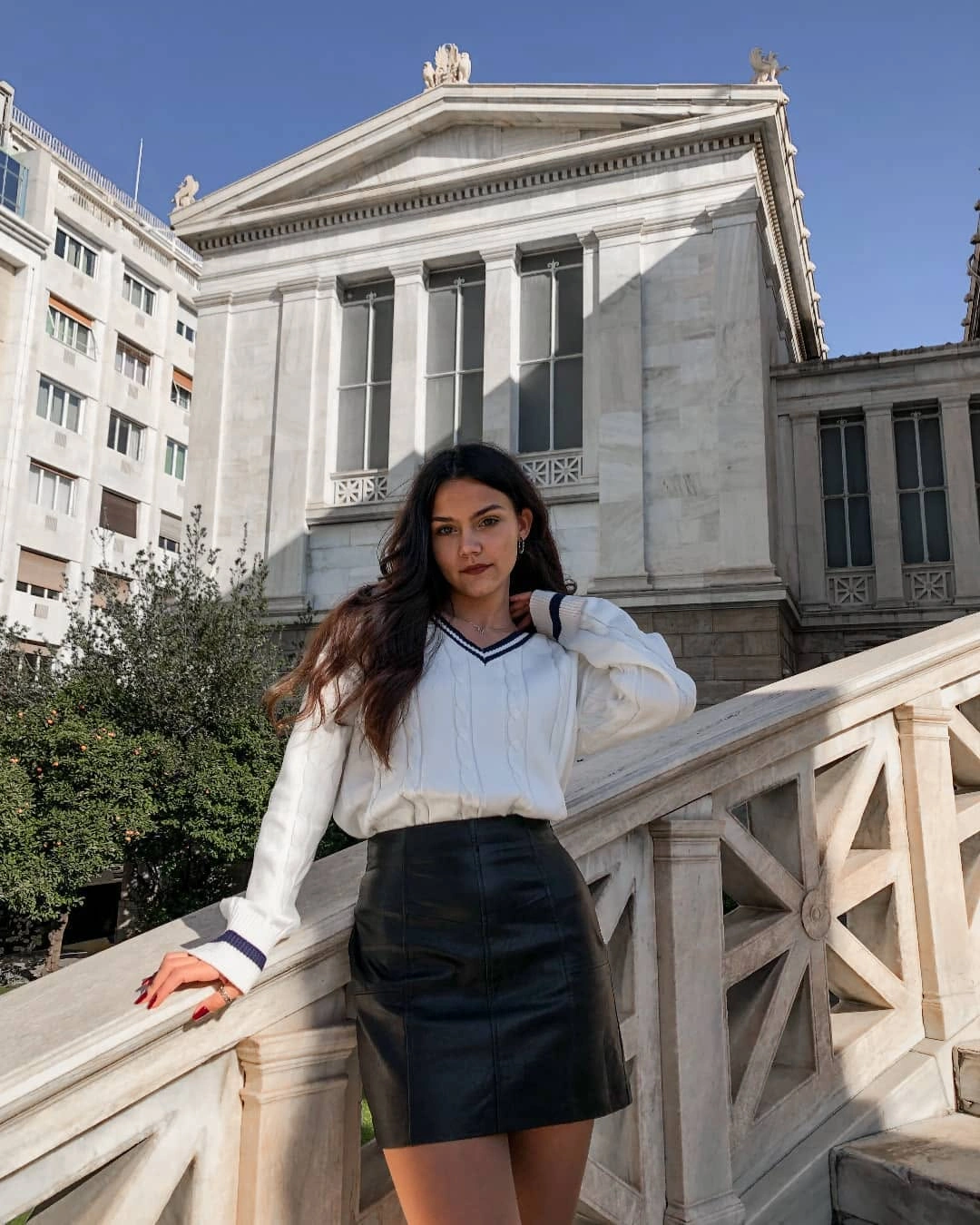 Cream V-neck sweater with dark trim and black mini skirt