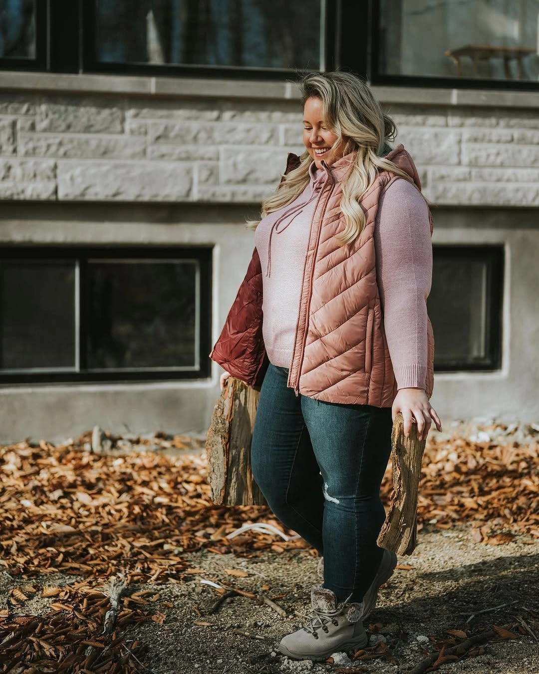 Woman in pink quilted vest, dark jeans, and light boots